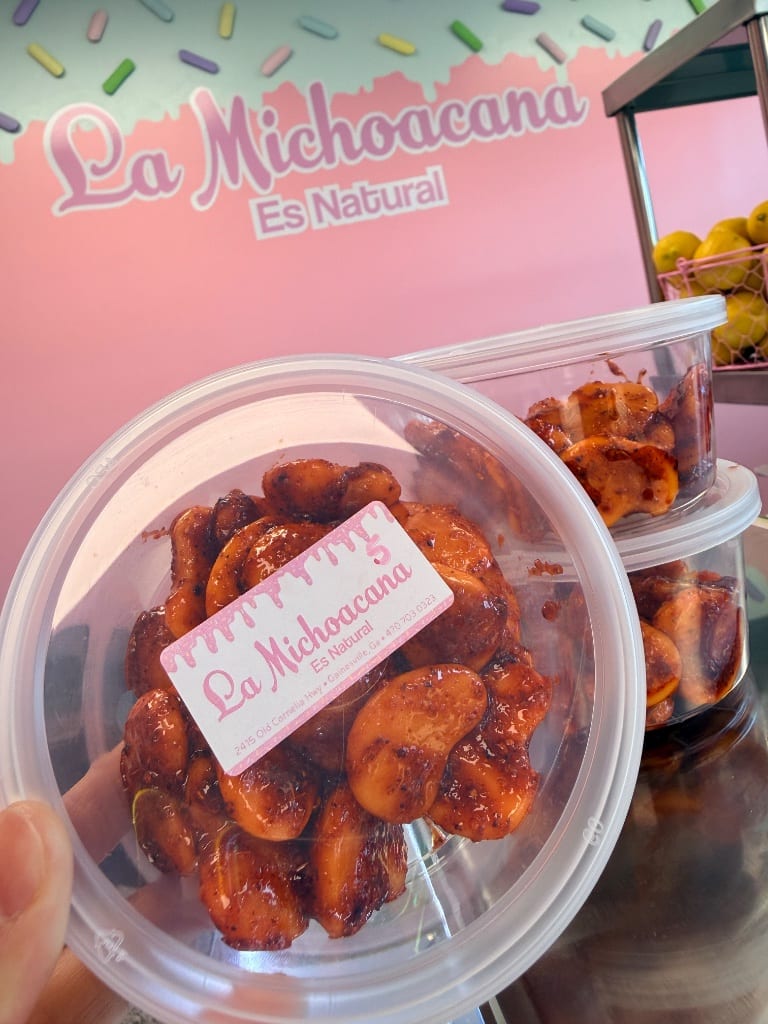 Tamarind candied nuts in a branded container